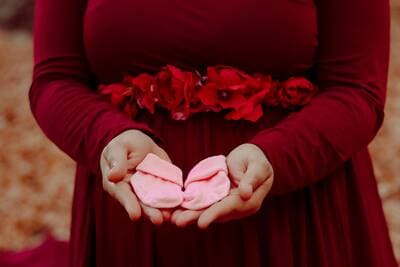 pregnant woman holding a pair of pink baby socks