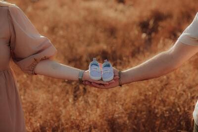 couple holding a pair of baby shoes