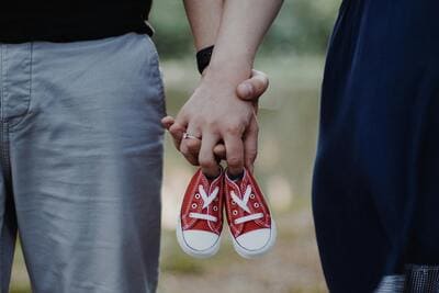 couple holding a pair of red baby shoes