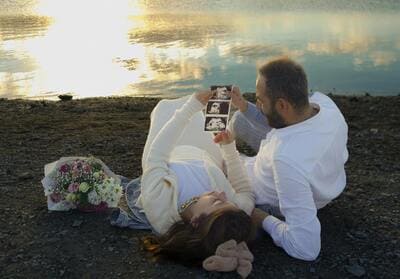 couple sitting by a lake looking at ultrasound pictures