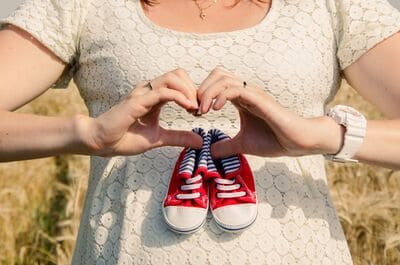 pregnant woman holding a pair of red and white shoes